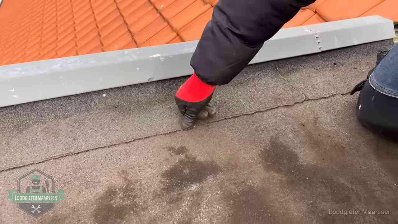 Lekkage bij de naad van een plat dak in Maarssen Vakman wijst een naad met vochtplekken aan op een bitumen plat dak in Maarssen
