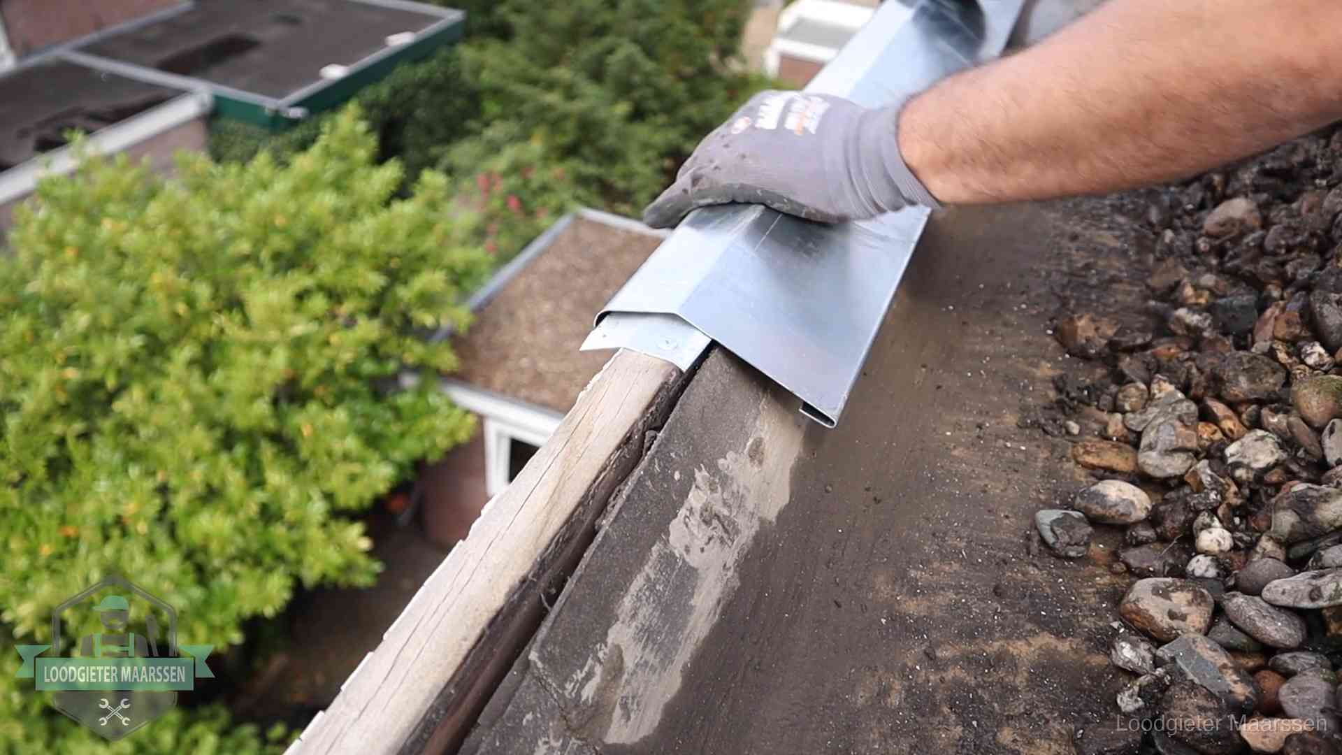 Daklekkage per wijk in Maarssen Dakdekker plaatst een zinken deklijst op een dakrand met uitzicht over een woonwijk in Maarssen