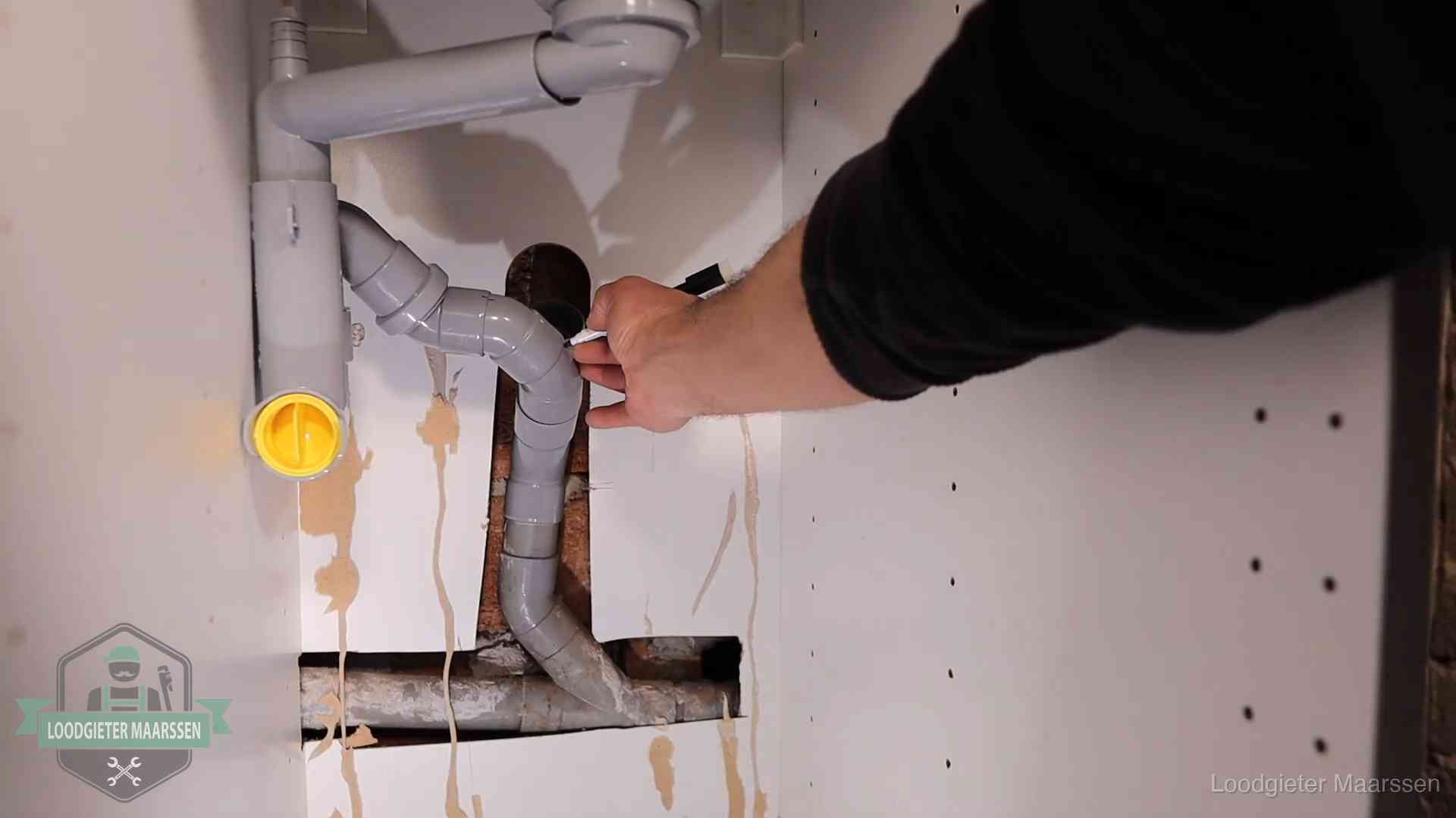 Loodgieter markeert een pvc-afvoerbuis onder een gootsteen in Maarssen