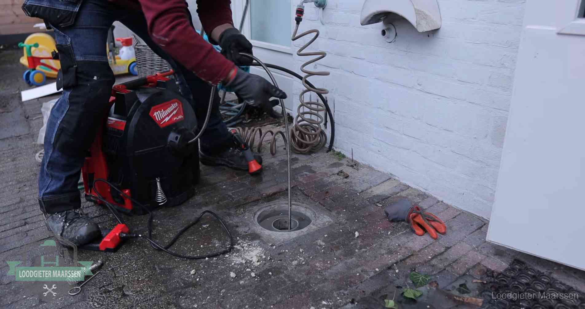 Ontstoppingsputje in de bestrating naast de gevel van een woning in Maarssen