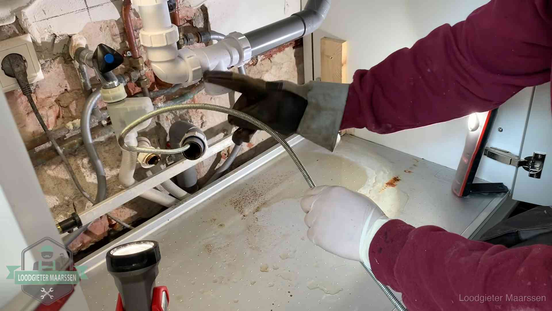Ontstoppingsveer gaat in een geopende sifonaansluiting onder het aanrecht in Maarssen