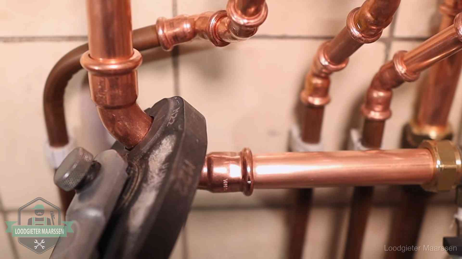 Persmachine perst een koperen fitting op nieuw leidingwerk in Maarssen