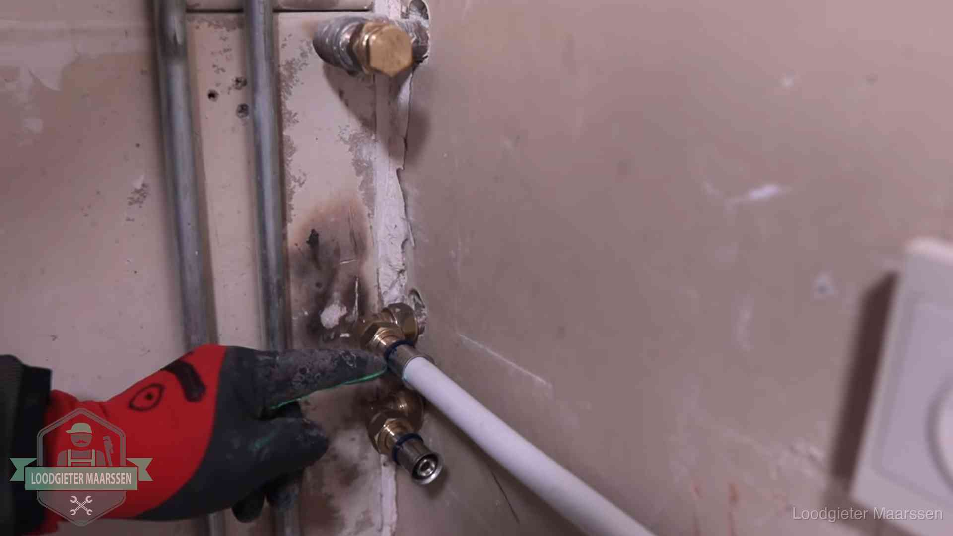 Loodgieter wijst de persfitting op nieuwe muuraansluitingen aan in een woning in Maarssen