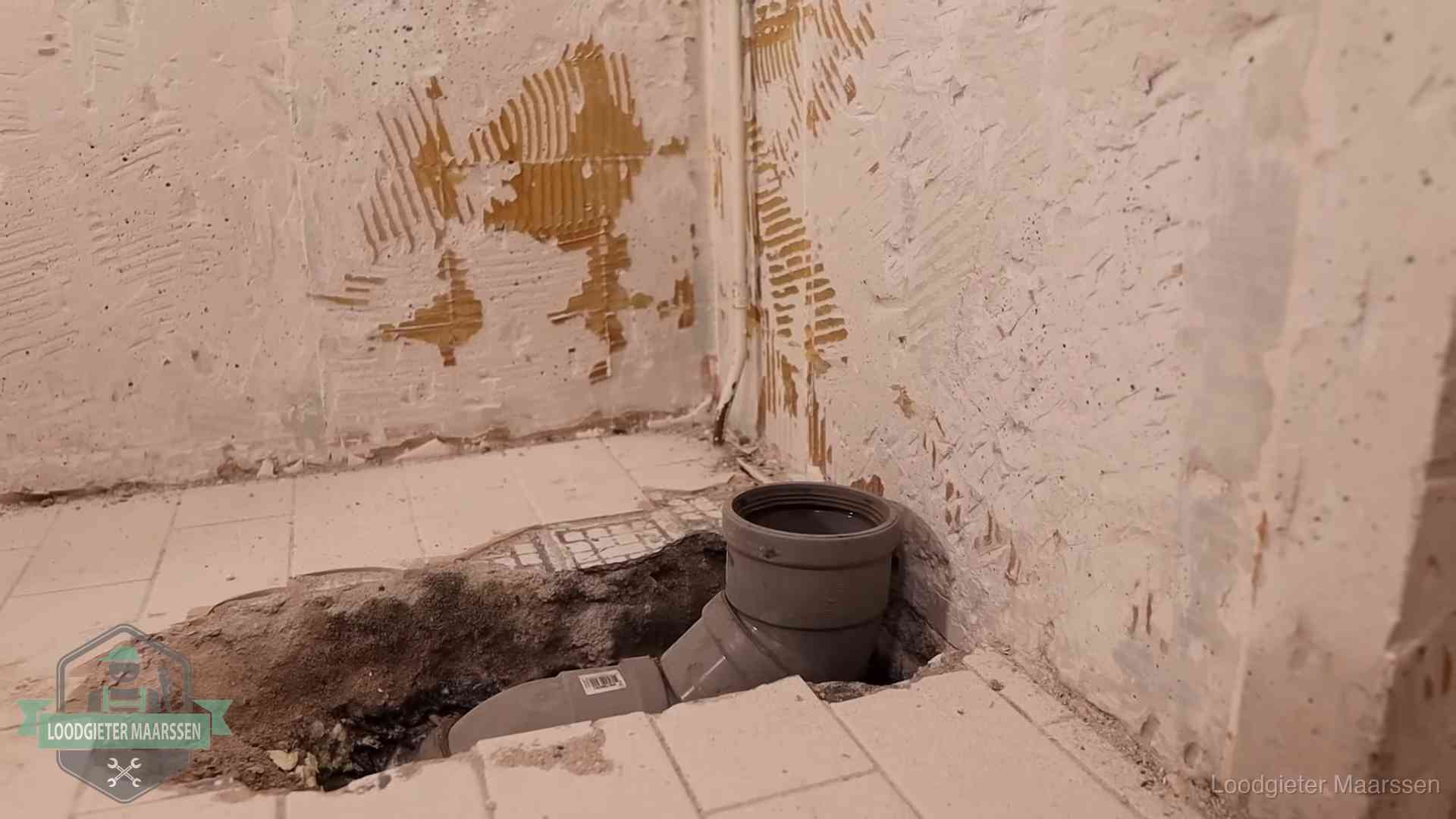 Opengebroken vloer met een nieuwe pvc-rioolbocht in een gegraven sleuf in Maarssen